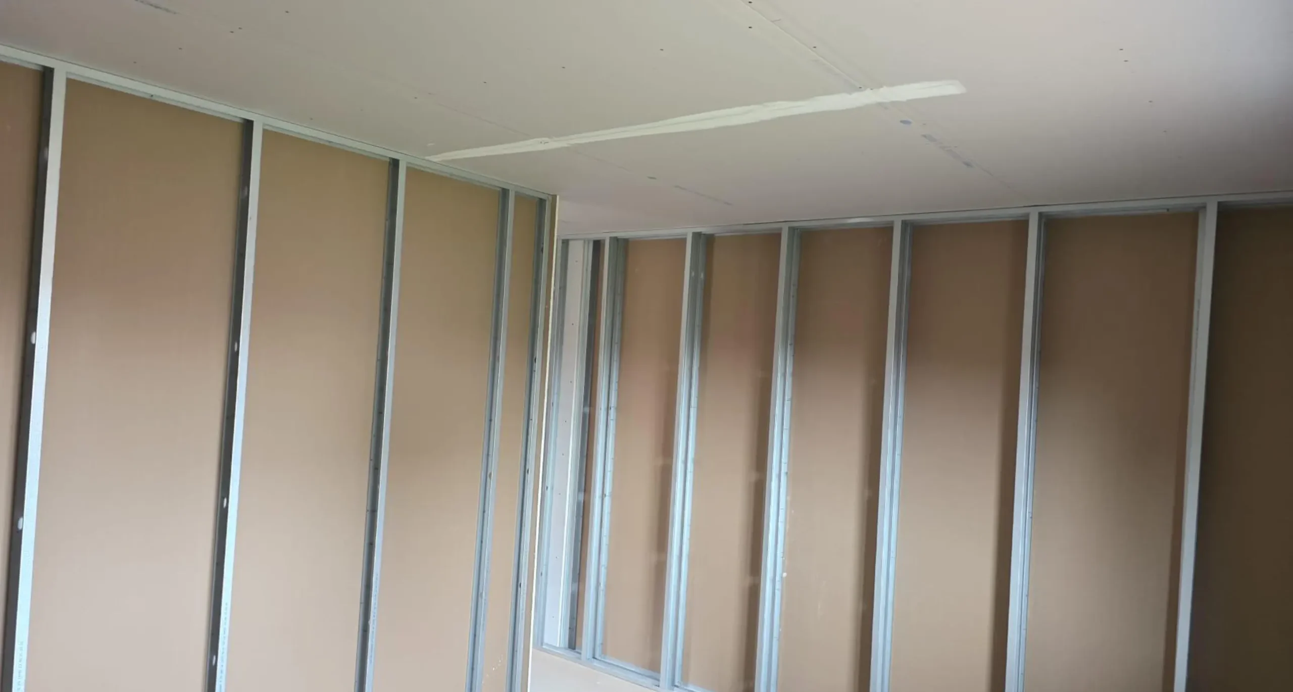 Chantier de plaquisterie dans le Sundgau avec faux plafond suspendu posé et plaque de plâtre hydrofuge verte visible sur le mur